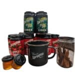 Cider cans labelled "Spreyton," a black mug, two small jars of honey, and a glass jar of cinnamon sticks arranged together.